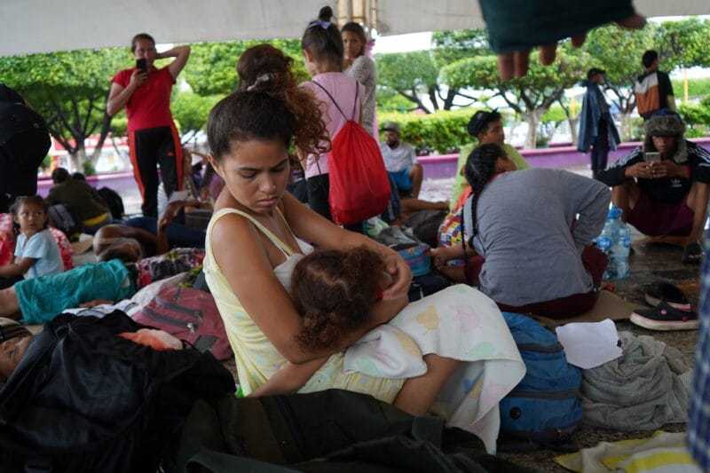 Migrante embarazada que viaja con dos hijas y su esposo resguardándose de la lluvia en la plaza de Ciudad Hidalgo a un lado del río Suchiate. Foto: Alicia Fernández