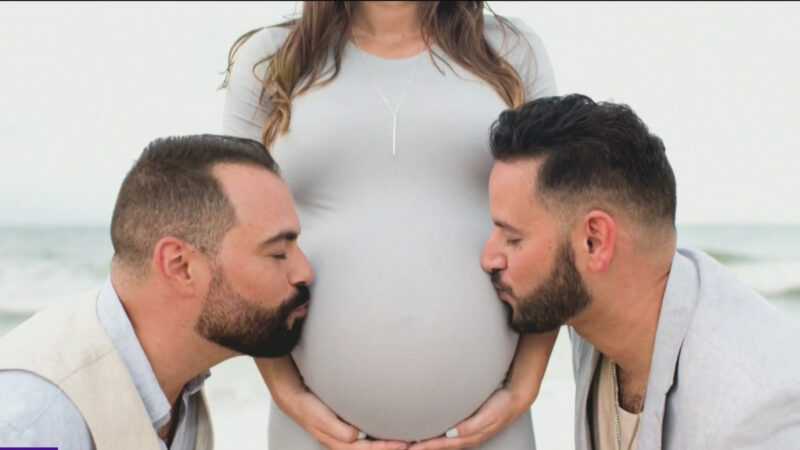 Foto de una pareja de hombres gays,  junto a mujer embarazada 